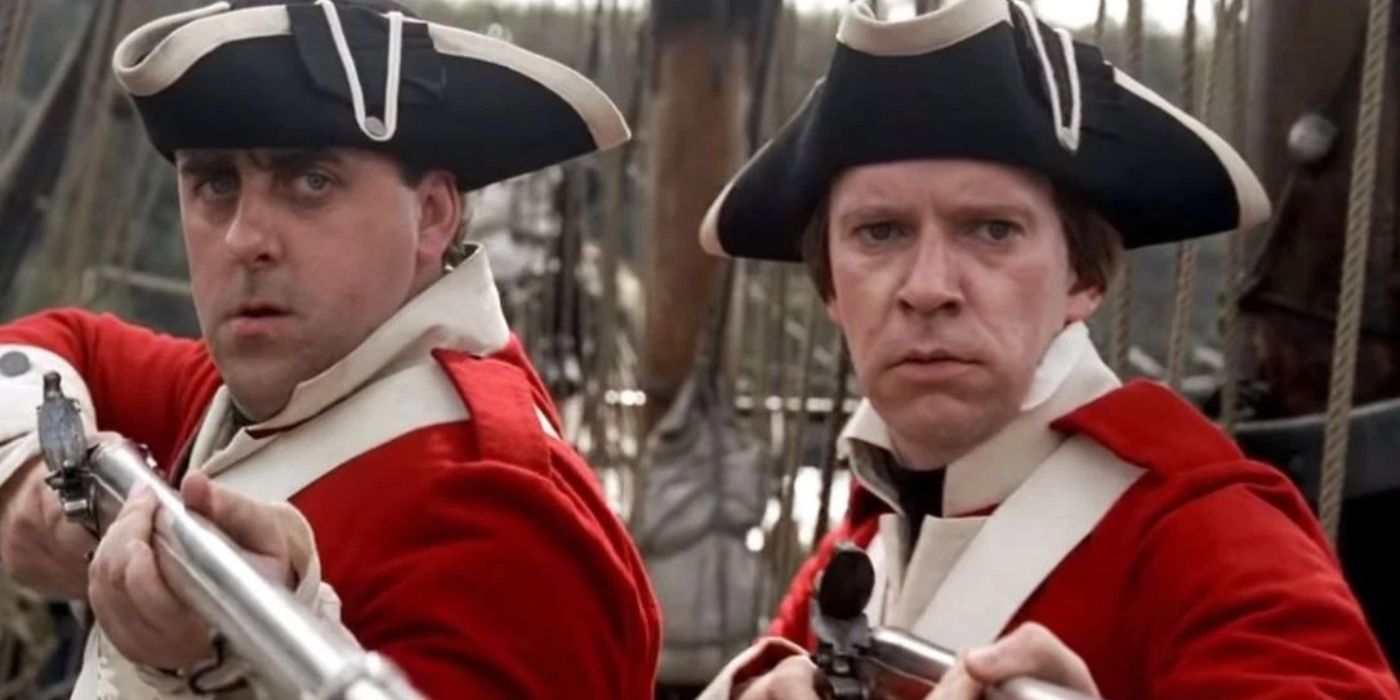 Murtogg and Mullroy stand in their red Navy uniforms, holding their rifles in 'Pirates of the Caribbean: The Curse of the Black Pearl' (2006)