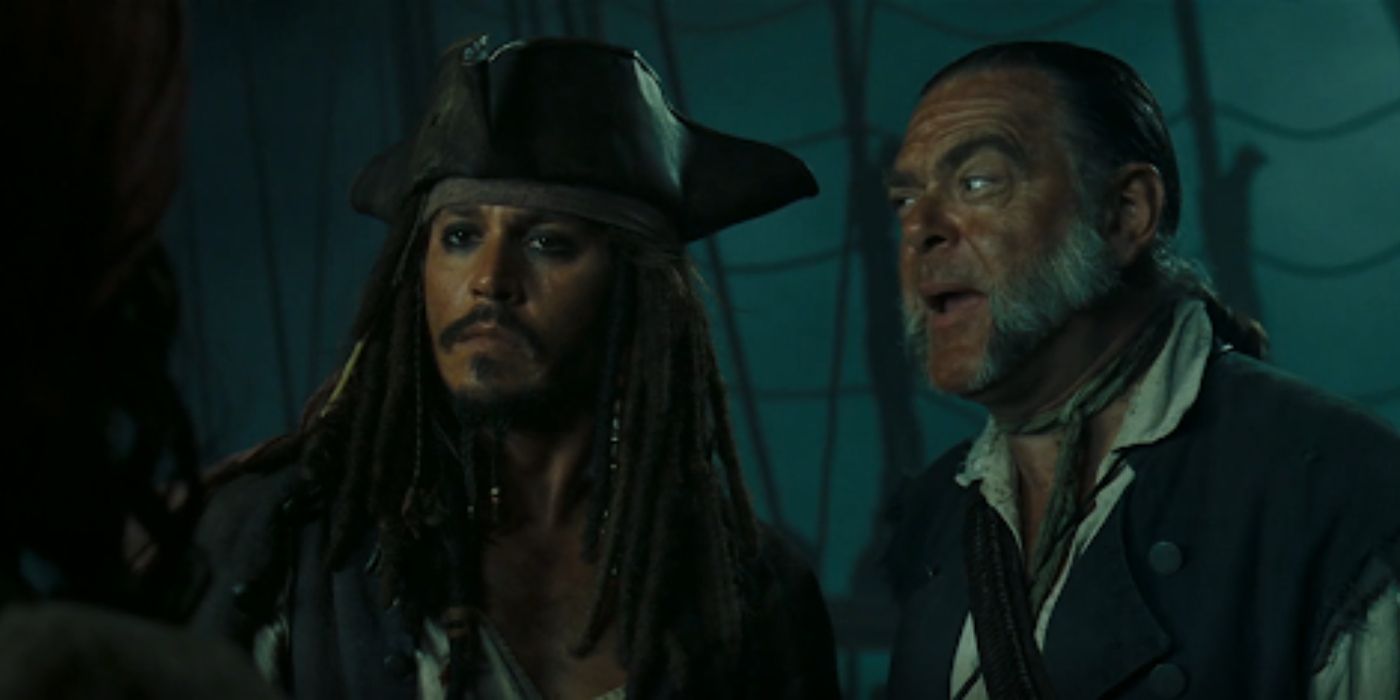 Mr. Gibbs offers advise to Jack Sparrow as they stand on the Black Pearl on a gloomy night in 'Pirates of the Caribbean: Dead Man's Chest' (2006).
