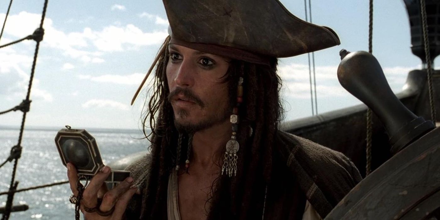 Captain Jack Sparrow stands at the helm of the Black Pearl, gazing out at he holds his compass in 'Pirates of the Caribbean: The Curse of the Black Pearl' (2003).