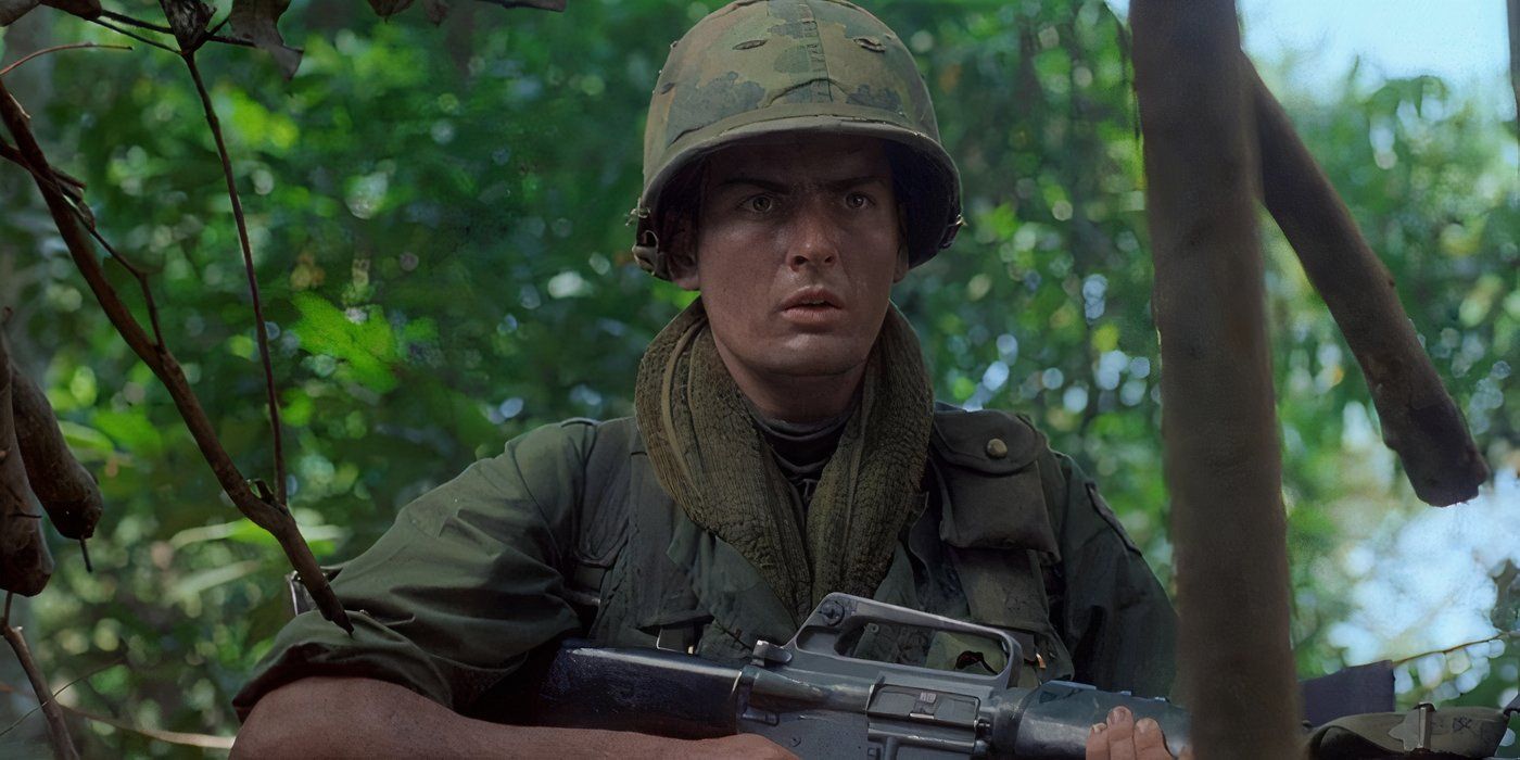 Chris holding a rifle in the jungle in 'Platoon' (1986)