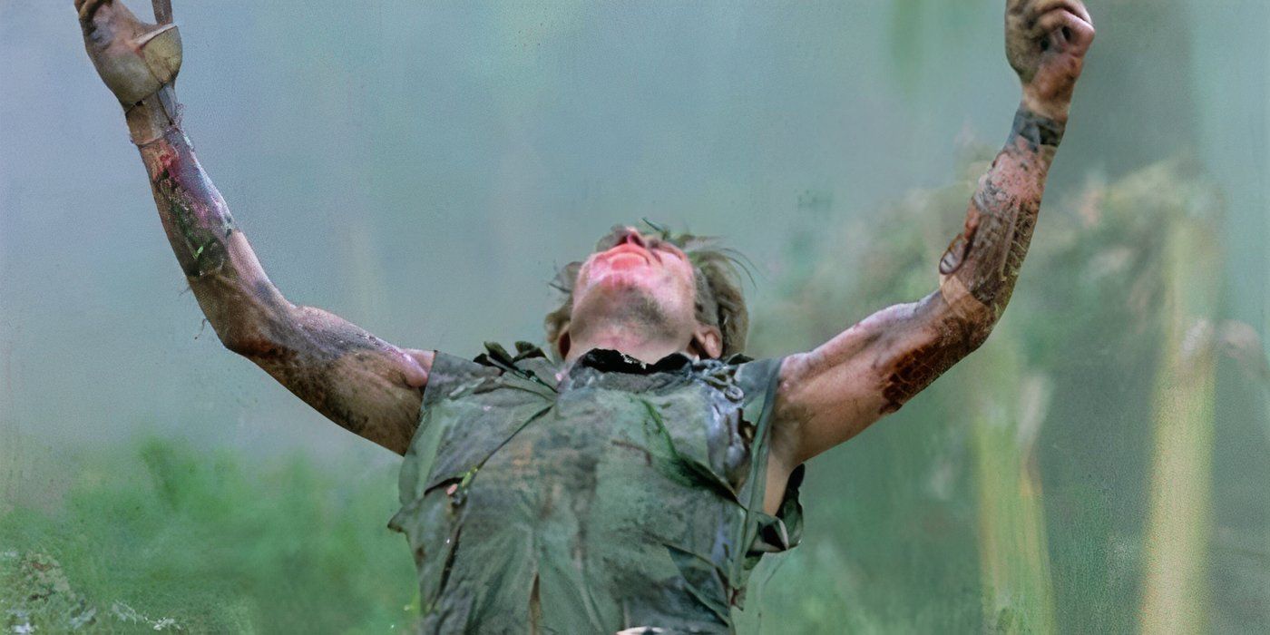 Elias (Willem Dafoe) raises his arms and falls to his knees as he is shot from behind in the jungle, in Platoon