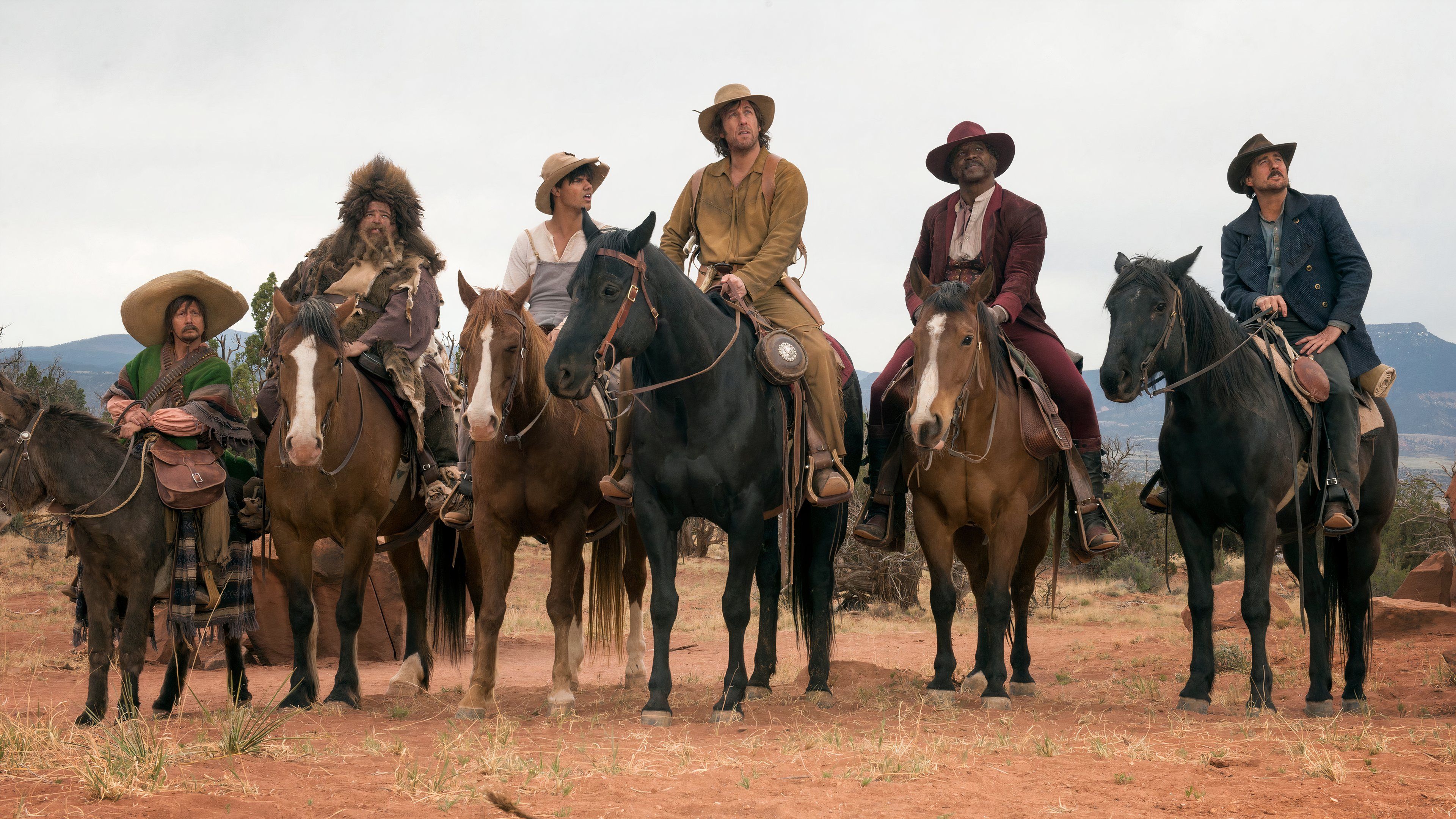 The cast of The Ridiculous 6 on horseback in line.