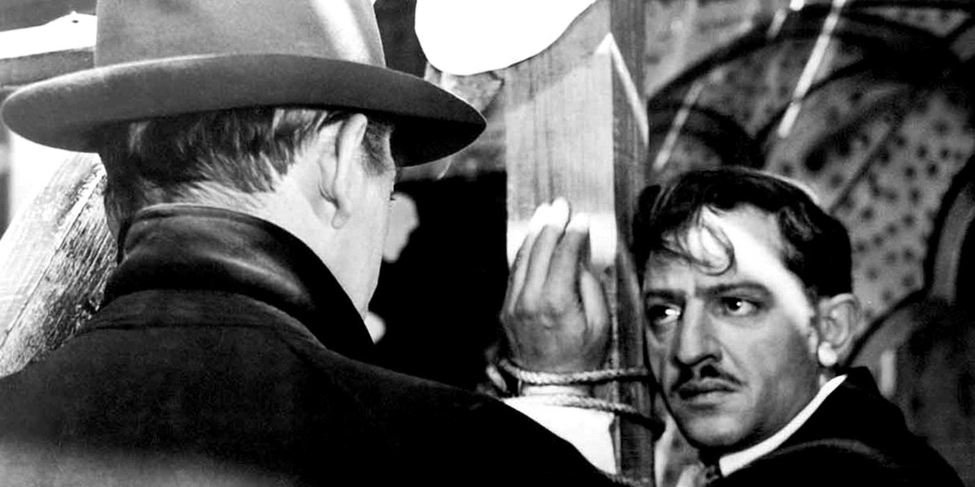 Jules Dassin como César "milanés" En Rififi, está atado a un pilar, mirando a una figura de espaldas a la pantalla.