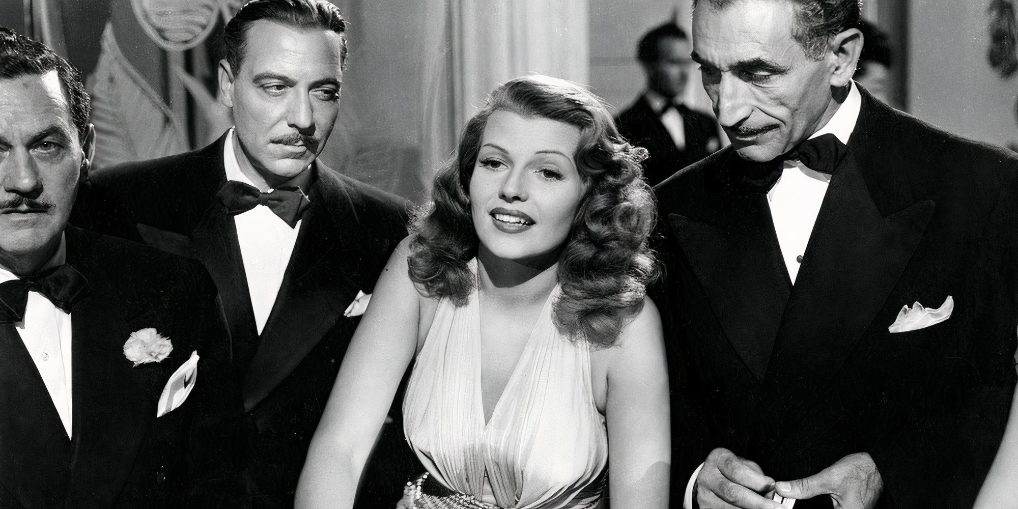 Rita Hayworth as Gilda, surrounded by three men in tuxedos