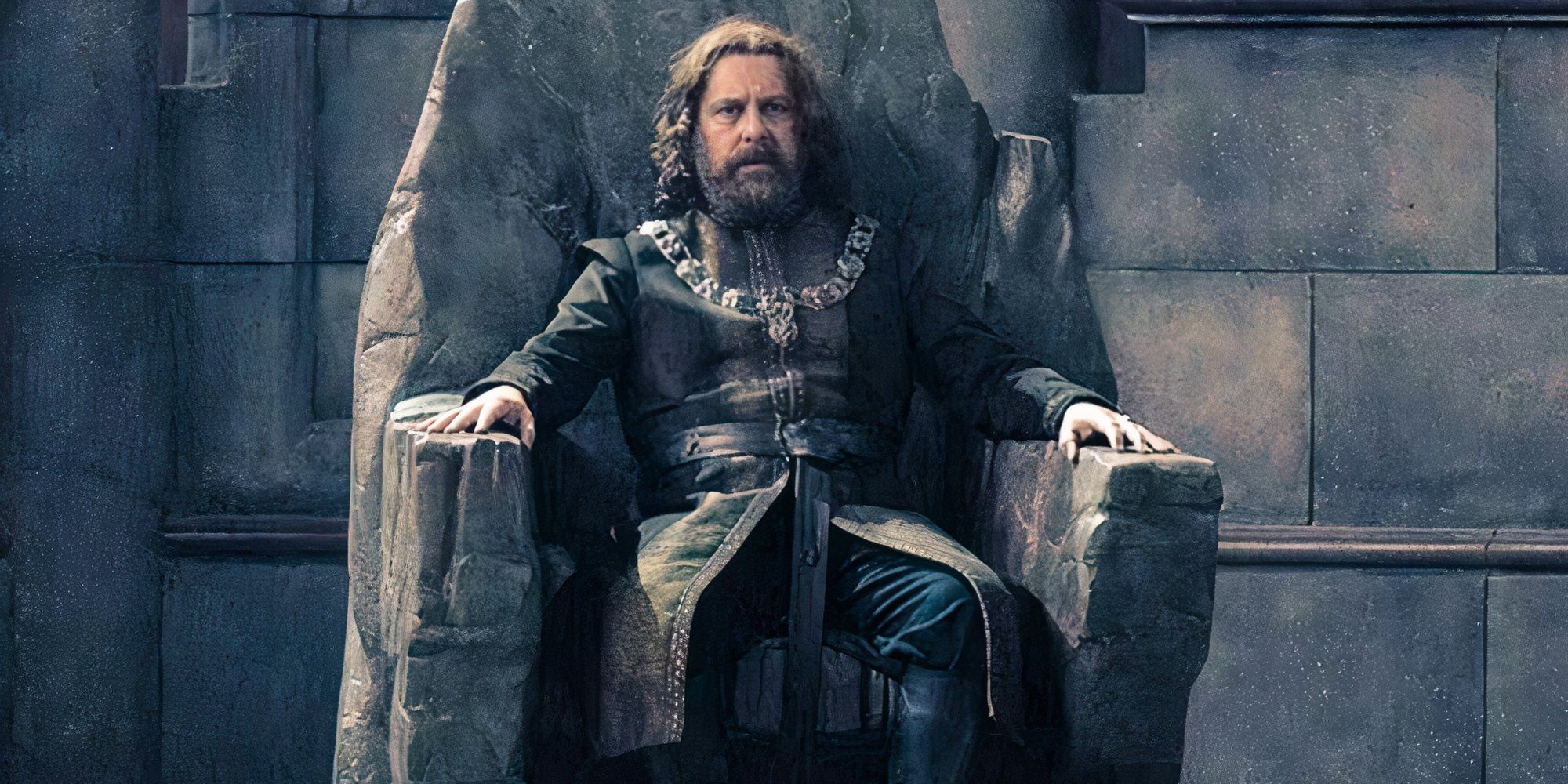 Roger Evans as Lord Barros Baratheon sitting in a cement throne in House of the Dragon