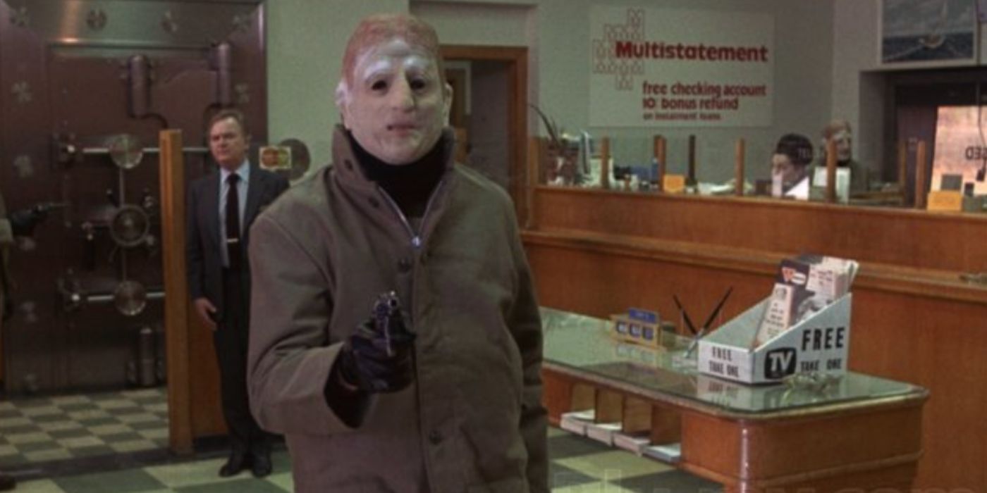 A bank robber holds a gun and wears a mask inside of a bank in 'The Friends of Eddie Coyle'
