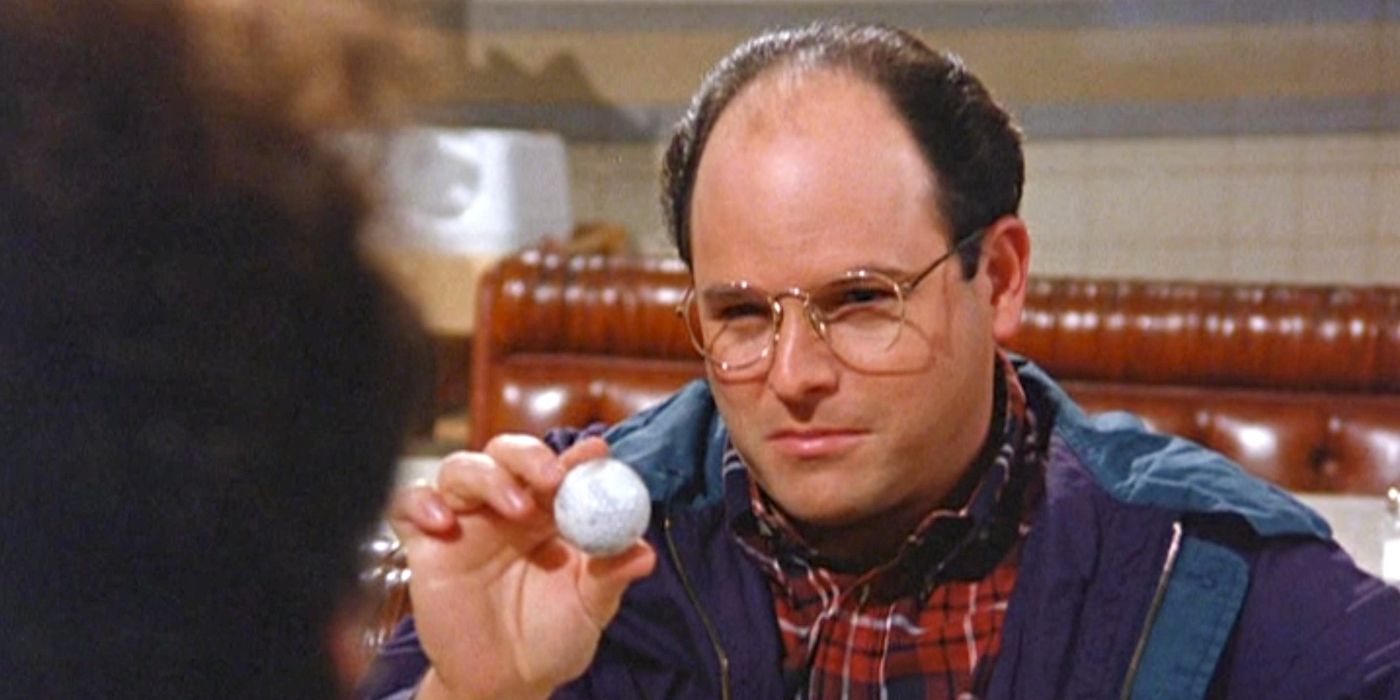 Jason Alexander as George Costanza, sitting in the diner holding up a golf ball
