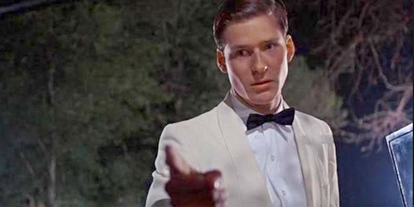 Crispin Glover as George McFly, wearing a white suit and a black tie, pointing angrily at someone off-camera in Back to the Future