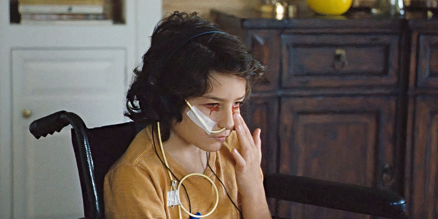 Sunny Suljic as Bob Murphy, sitting in a wheelchair with a feeding tube, touching his face as blood drips from his eyes in The Killing of a Sacred Deer