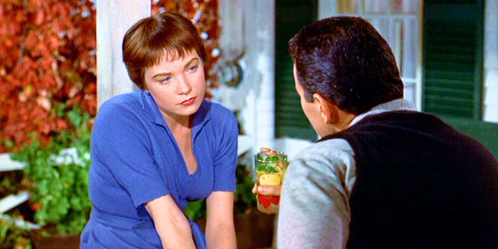 Shirley MacLaine sitting and looking at a man with his back to the camera in The Trouble with Harry (1955)