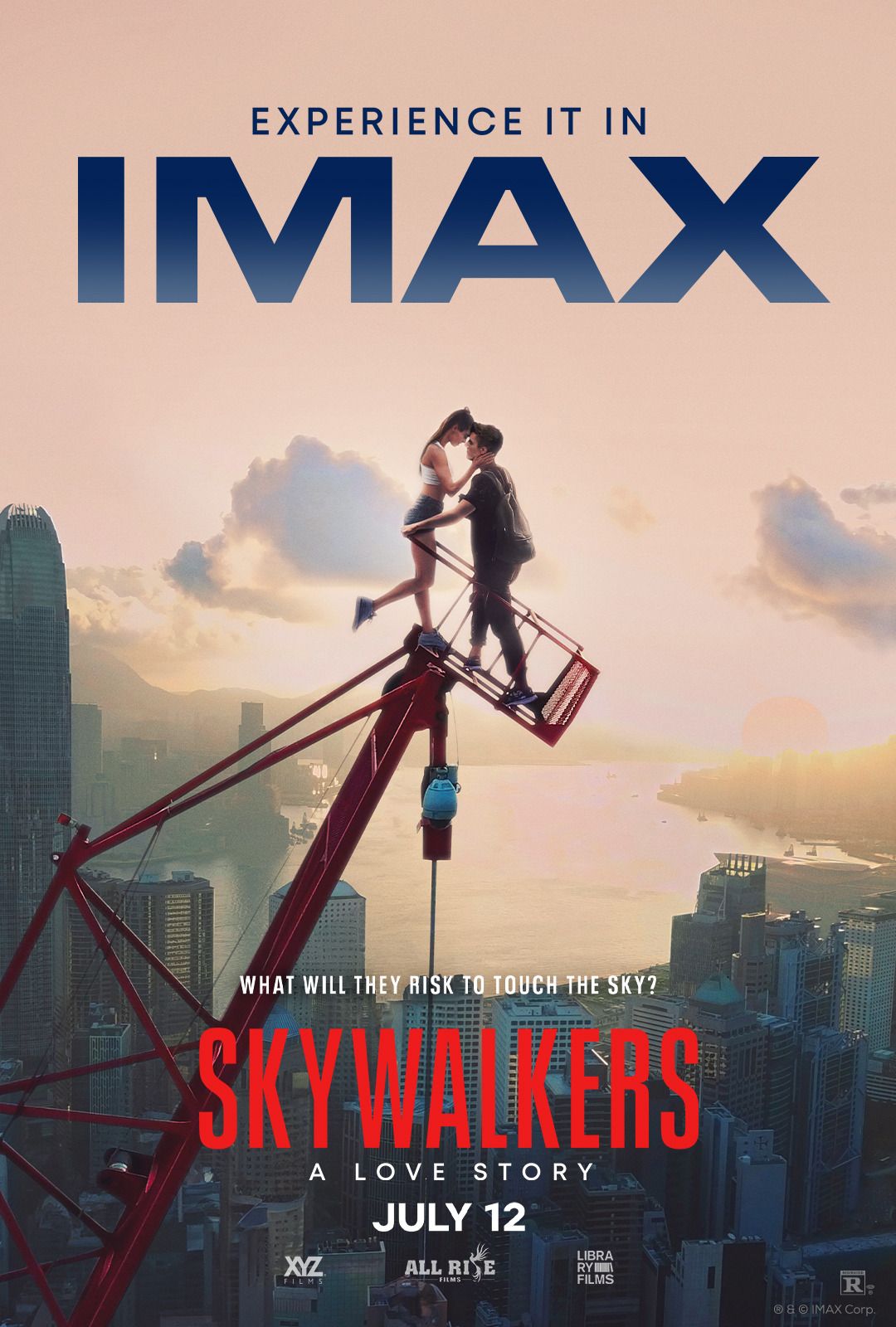 A couple poses on top of a skyscraper silhouetted at sunset on an IMAX poster.