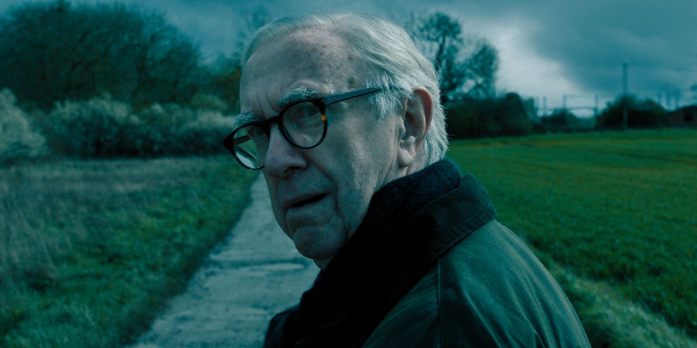 Jonathan Pryce walks down a grassy path, and looks back afraid in Slow Horses Season 4