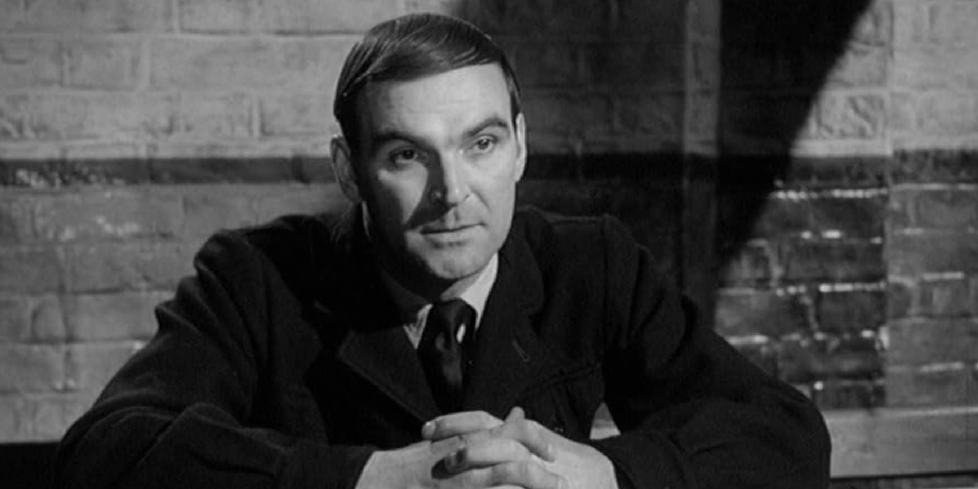 Una fotografía en blanco y negro de Stanley Baker, quien interpreta a Johnny Bunnion en 