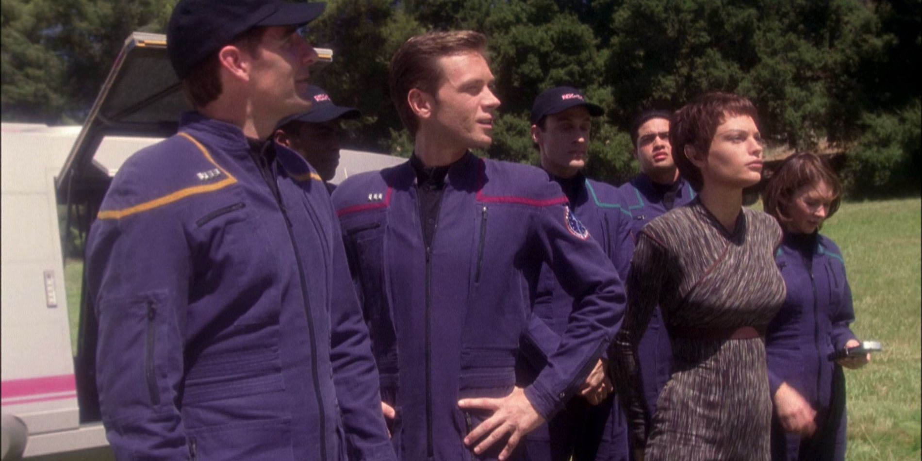 Crew members stand in a field and look into the distance in the 'Star Trek: Enterprise' TV series.