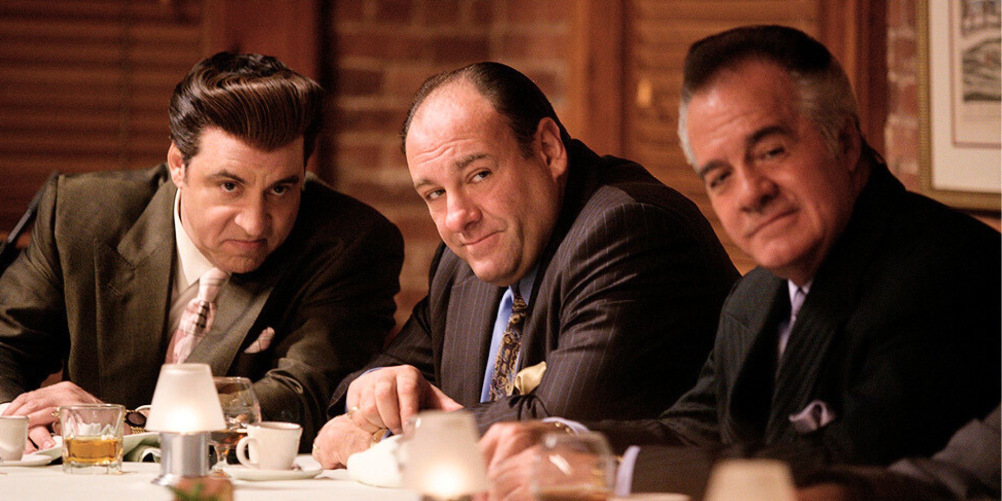 Steven Van Zandt, James Gandolfini and Tony Sirico sitting next to each other at a table in The Sopranos