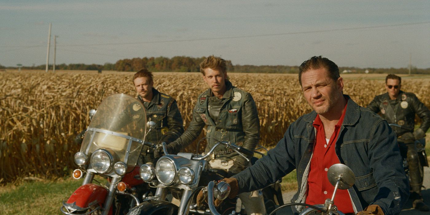 Tom Hardy, Austin Butler, and Boyd Holbrook looking to camera on their motorcycles in front of a cornfield 
