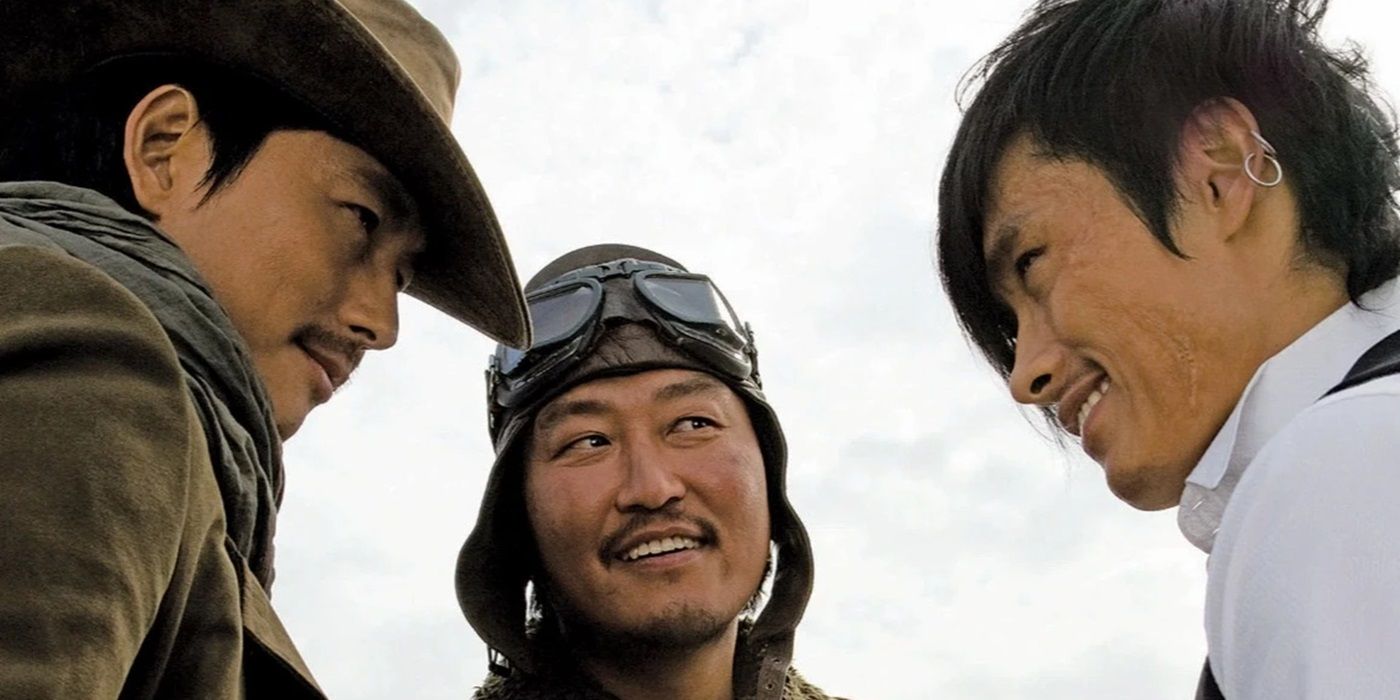 Song Kang-ho, Lee Byung-hun, and Jung Woo-sung huddled together & smiling in The Good, the Bad and the Weird