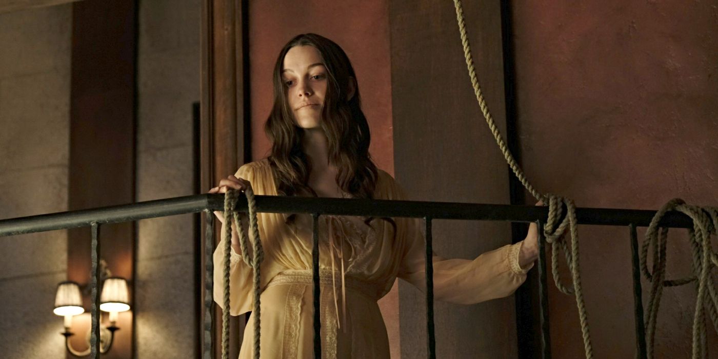 Victoria Pedretti as Nell Crain, wearing a night gown and standing on a balcony next to a rope in The Haunting of Hill House