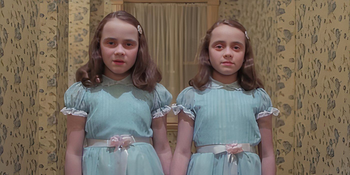 The Grady girls, played by Lisa and Louise Burns, stand together in a hallway in The Shining