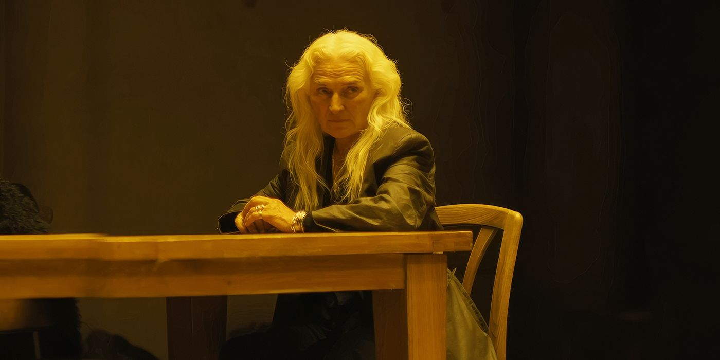 Olwen Fouéré as Madeline sits at a table looking suspicious in The Watchers. 