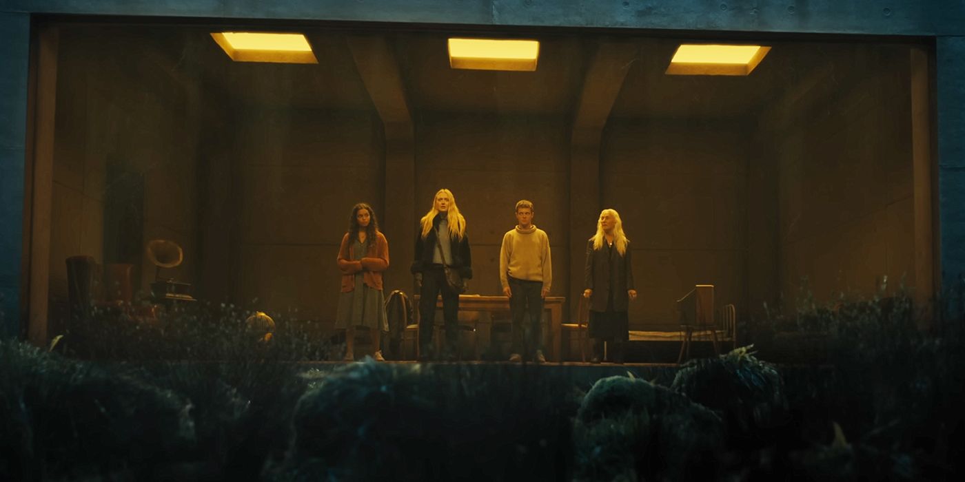 A group stands in a room in front of a one-way mirror in a still from The Watchers. 