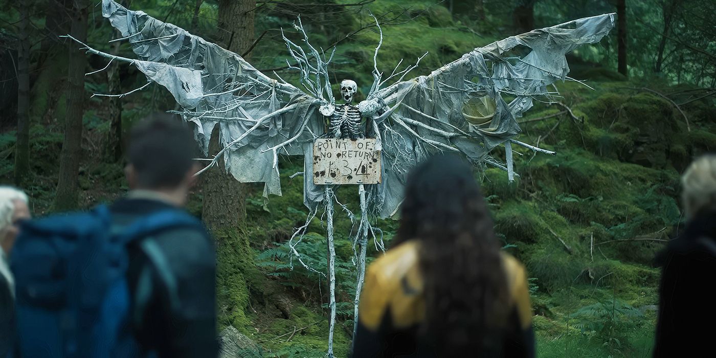 A group gathers in front of a skeleton with a sign that says "point of no return" in a still from The Watchers. 