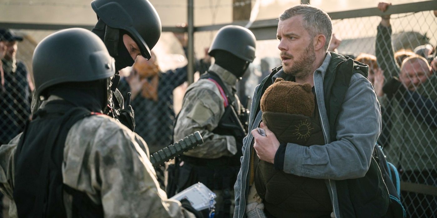 Russell Tovey, wearing a baby carrier, faces armoured soldiers in The Fortress