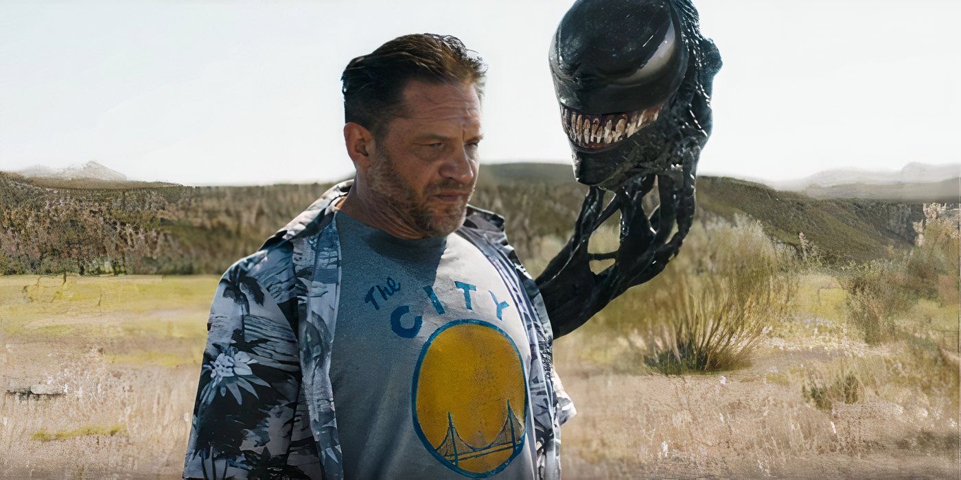 Tom Hardy as Eddie Brock standing in the desert with Venom's head attached to his back.