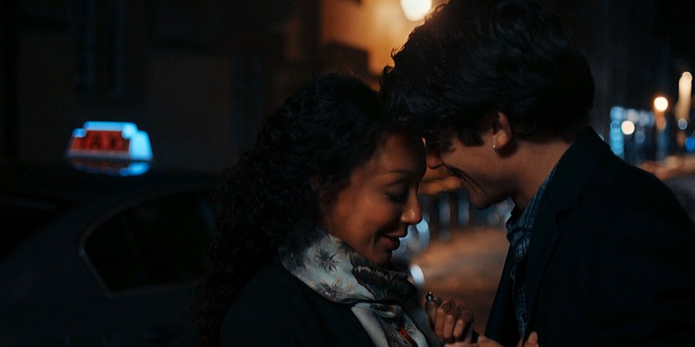 Marcus (Edward Bluemel) and Phoebe (Adelle Leonce) nuzzling their foreheads together and grinning on a dark city sidewalk in A DIscovery of Witches