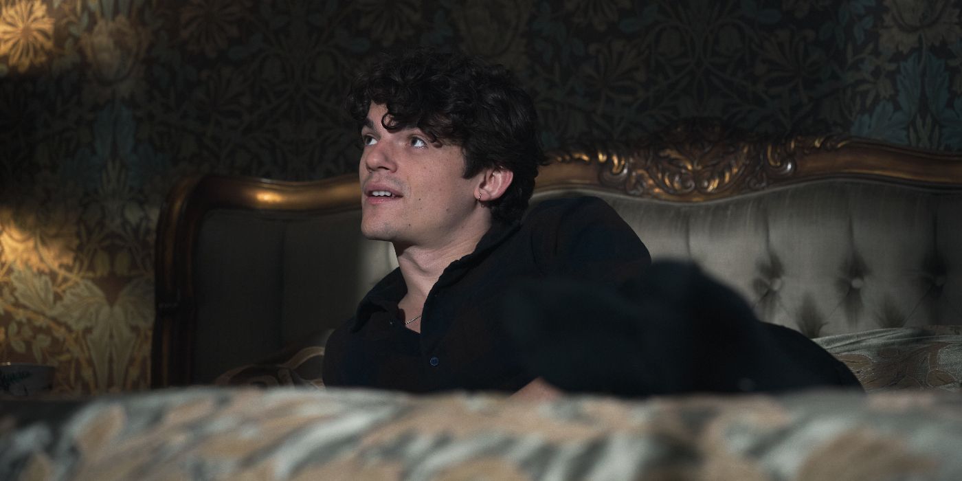 Marcus Whitmore (Edward Bluemel) lounging on a bed and looking offscreen to the right with a pleasant expression in A Discovery of Witches