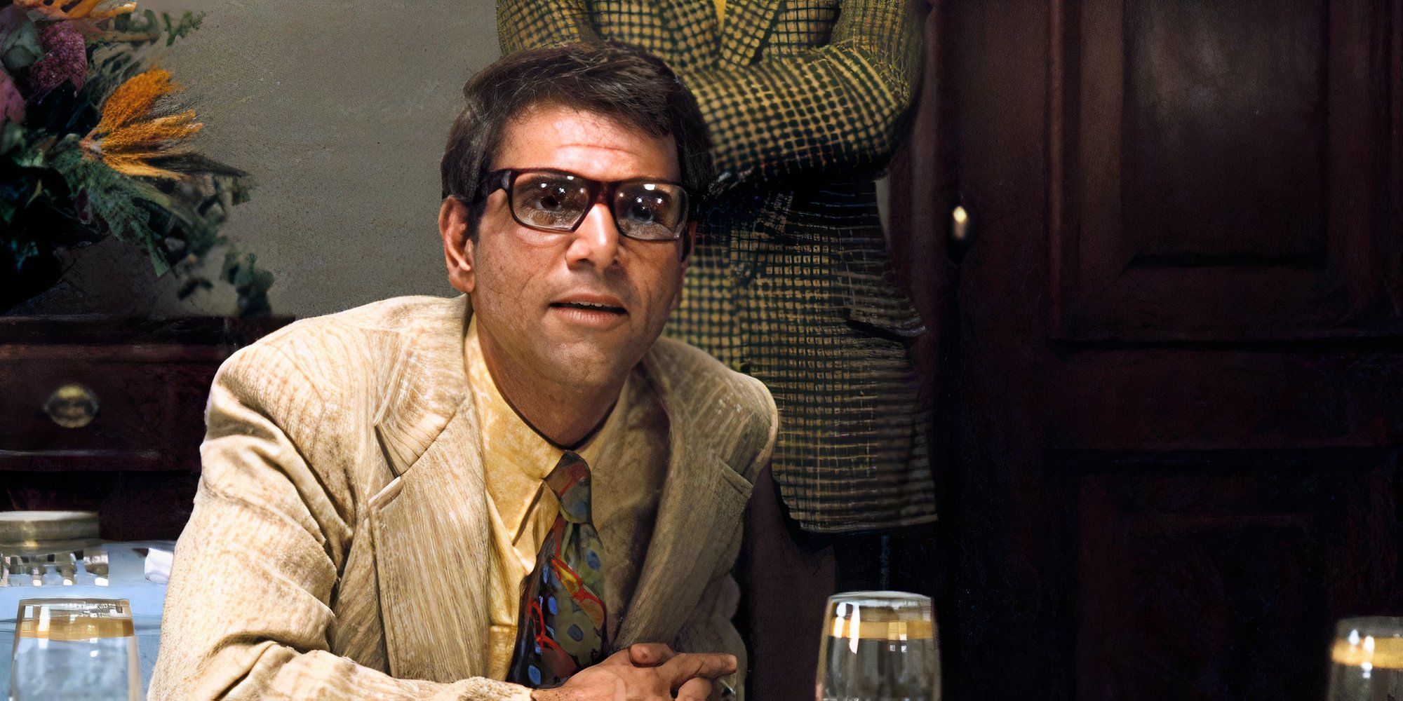 Alex Rocco as Moe Greene sitting at a table in The Godfather (1972)