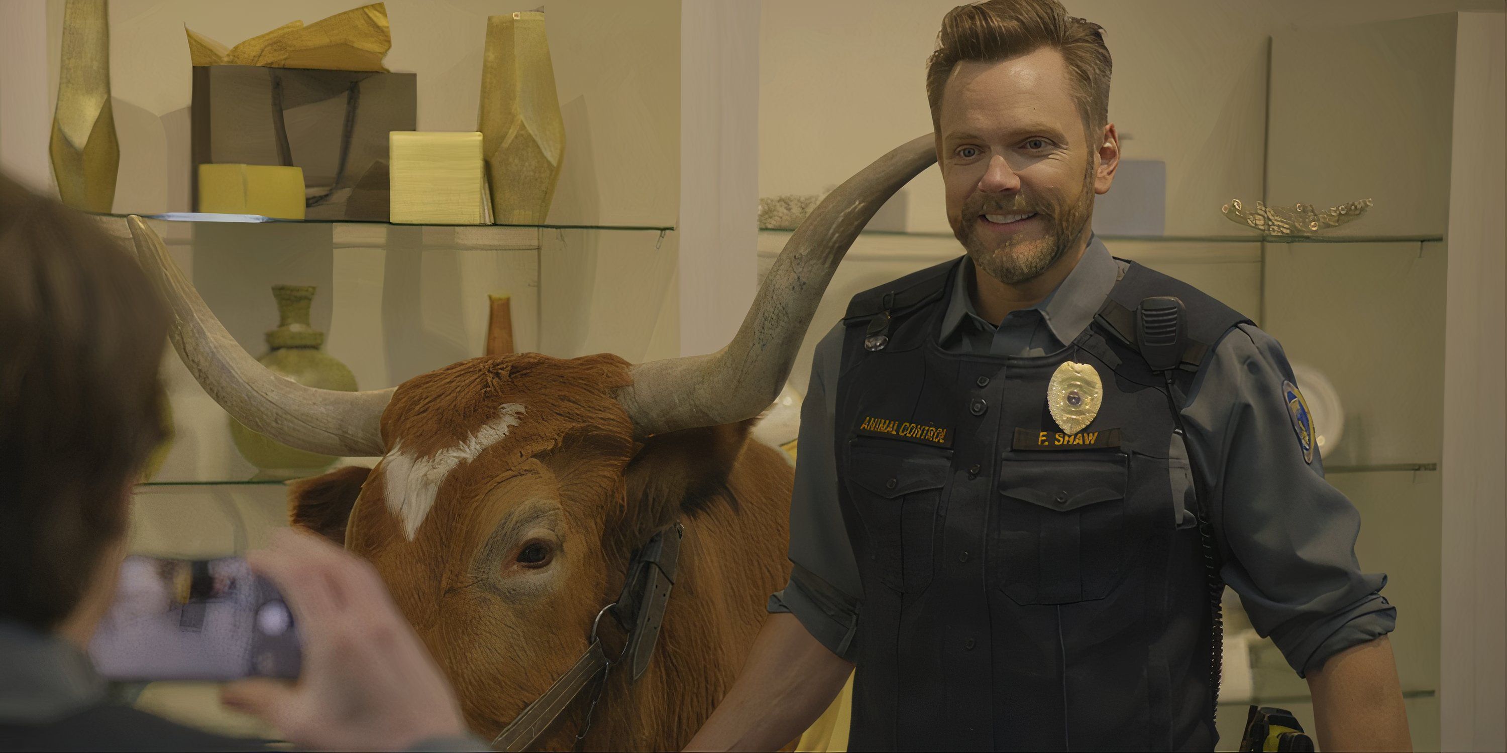 Joel McHale sonríe para una foto junto a un toro en Animal Control.