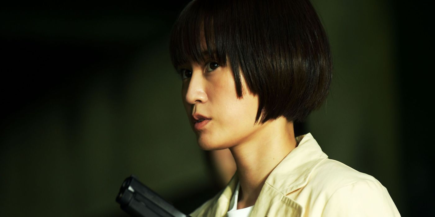A young girl holds a gun in a shadowy room in Baby Assassins Nice Days.