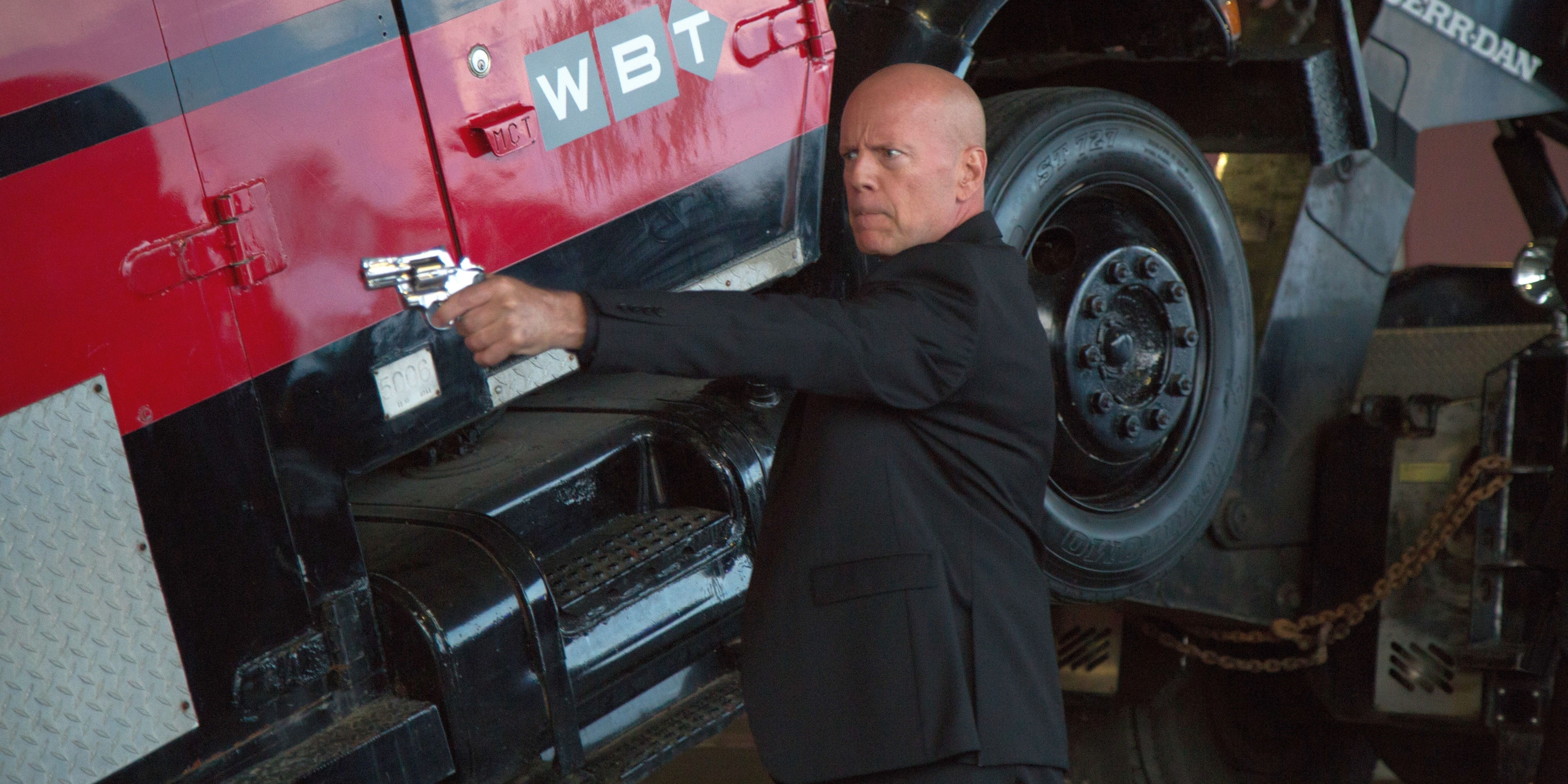 Bruce Willis pointing a gun in front of a red truck being repaired in &lsquo;Precious Cargo&rsquo;