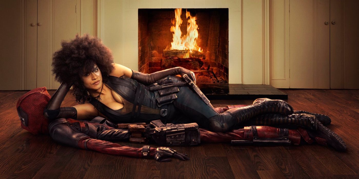 Domino (Zazie Beetz) lounging on Deadpool's folded suit on the floor in front of a fireplace in Deadpool 2