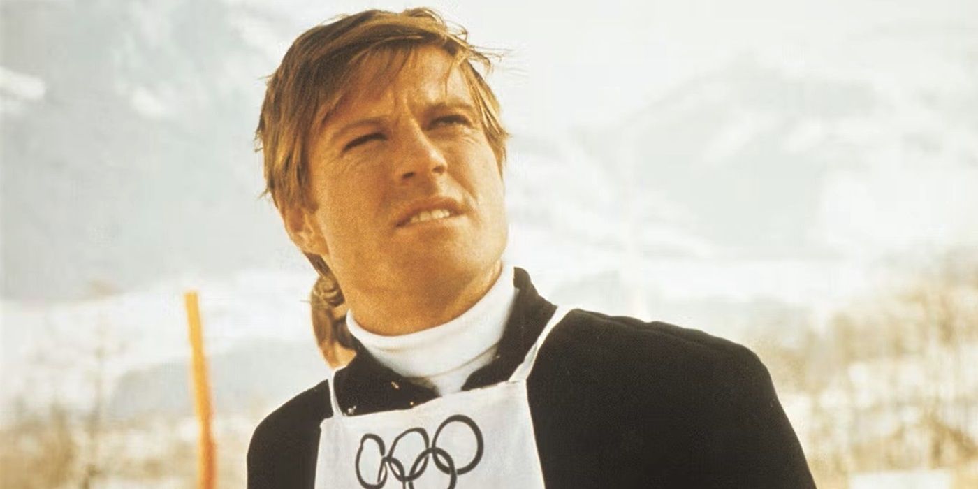 Robert Redford (corredor de descenso) como David Chappellette mira fuera de la pantalla con etiquetas olímpicas.