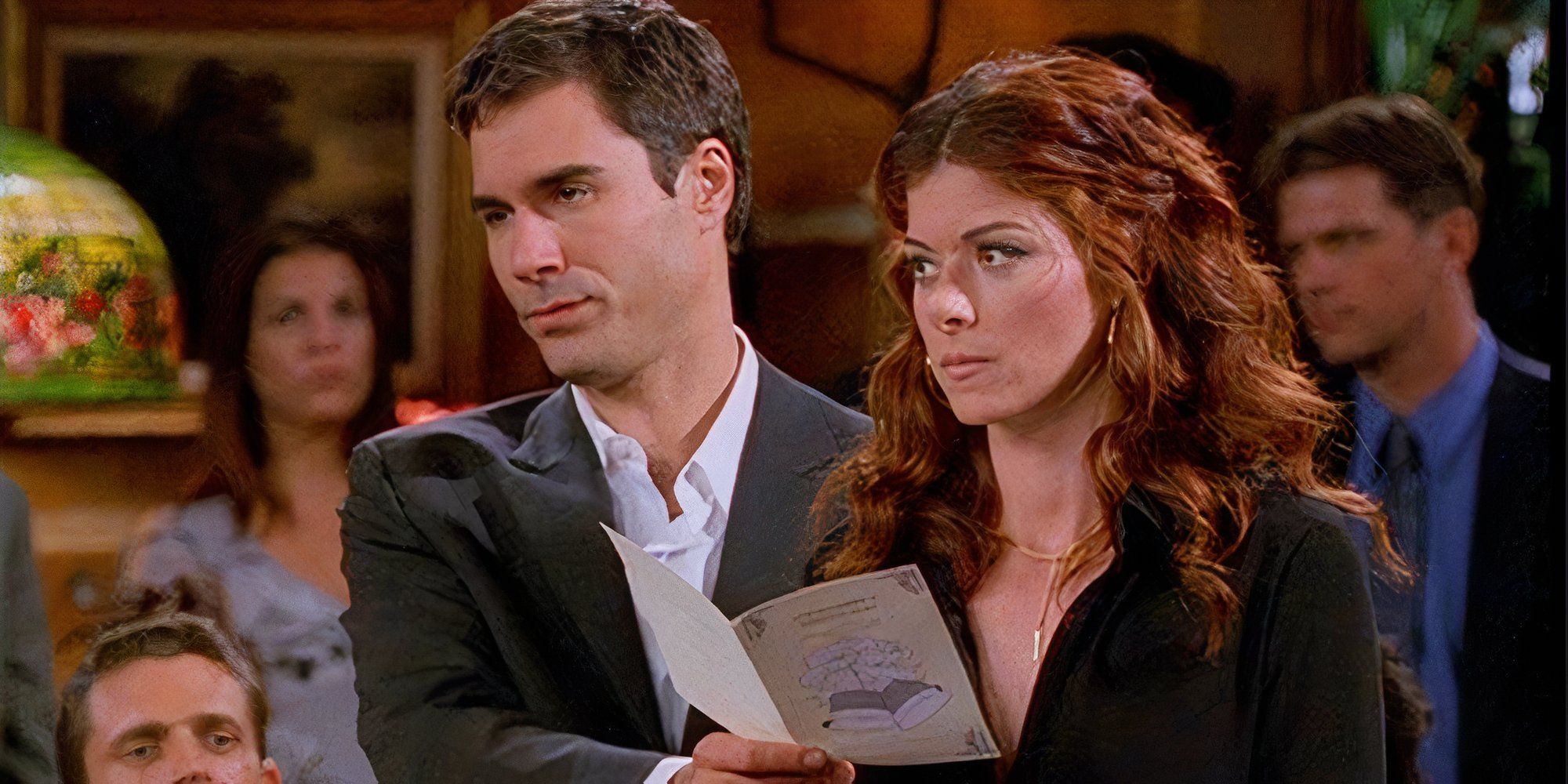 Eric McCormack as Will Truman holding a card open in front of Debra Messing as Grace Adler in Will & Grace