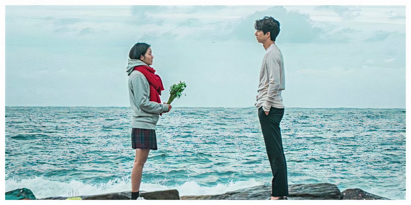 Eun-tak holding flowers while staring at Kim Shin standing on rocks in front of water in Goblin.