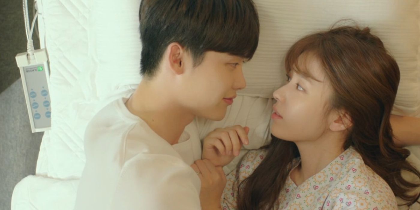 Han Hyo-joo and Lee Jong-suk laying in a hospital bed facing each other and smiling in W Two Worlds.