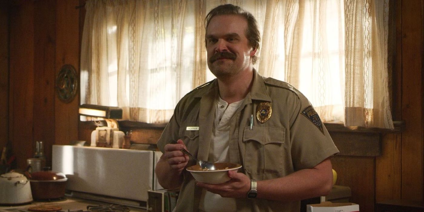 Hopper (David Harbour) eats a bowl of cereal with a slight smile on his face in 'Stranger Things'