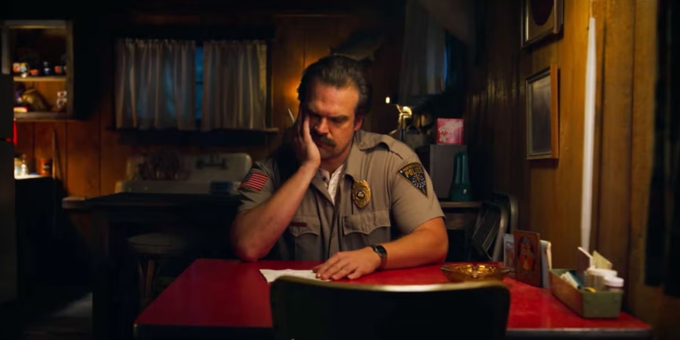 Hopper (David Armour) sits at a table in contemplation as he writes a note in 'Stranger Things'