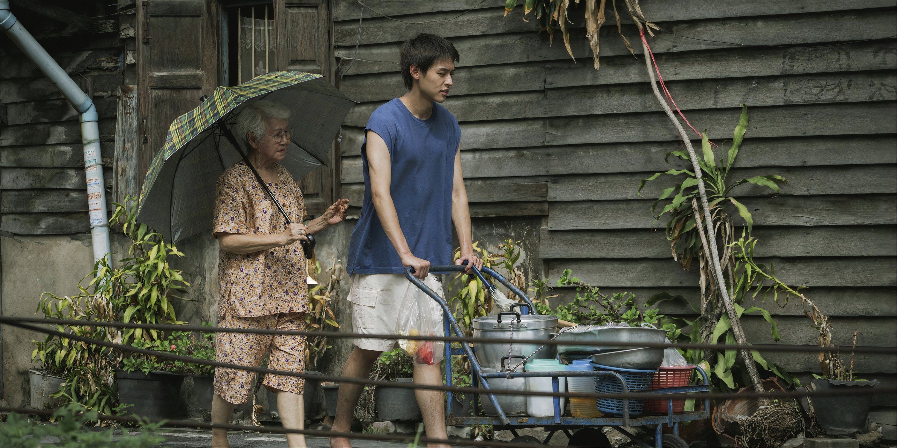 A boy pushes a cart walking next to his grandma (Usha Seamkhum) in How to Make Millions Before Grandma Dies