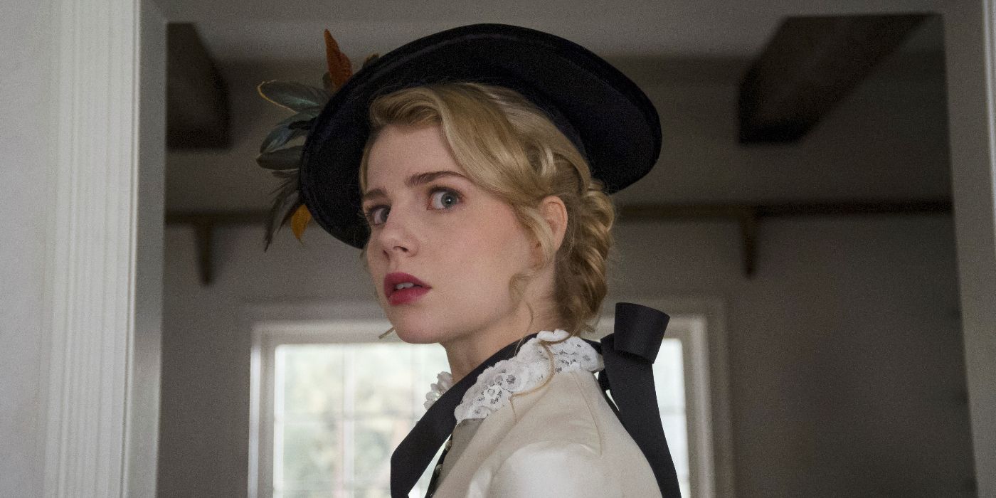 A close up of Polly (Lucy Boynton) wearing a white Victorian-era gown and a black hat, staring offscreen slightly ahead and to the left with a frightened expression in I Am the Pretty Thing That Lives in the House