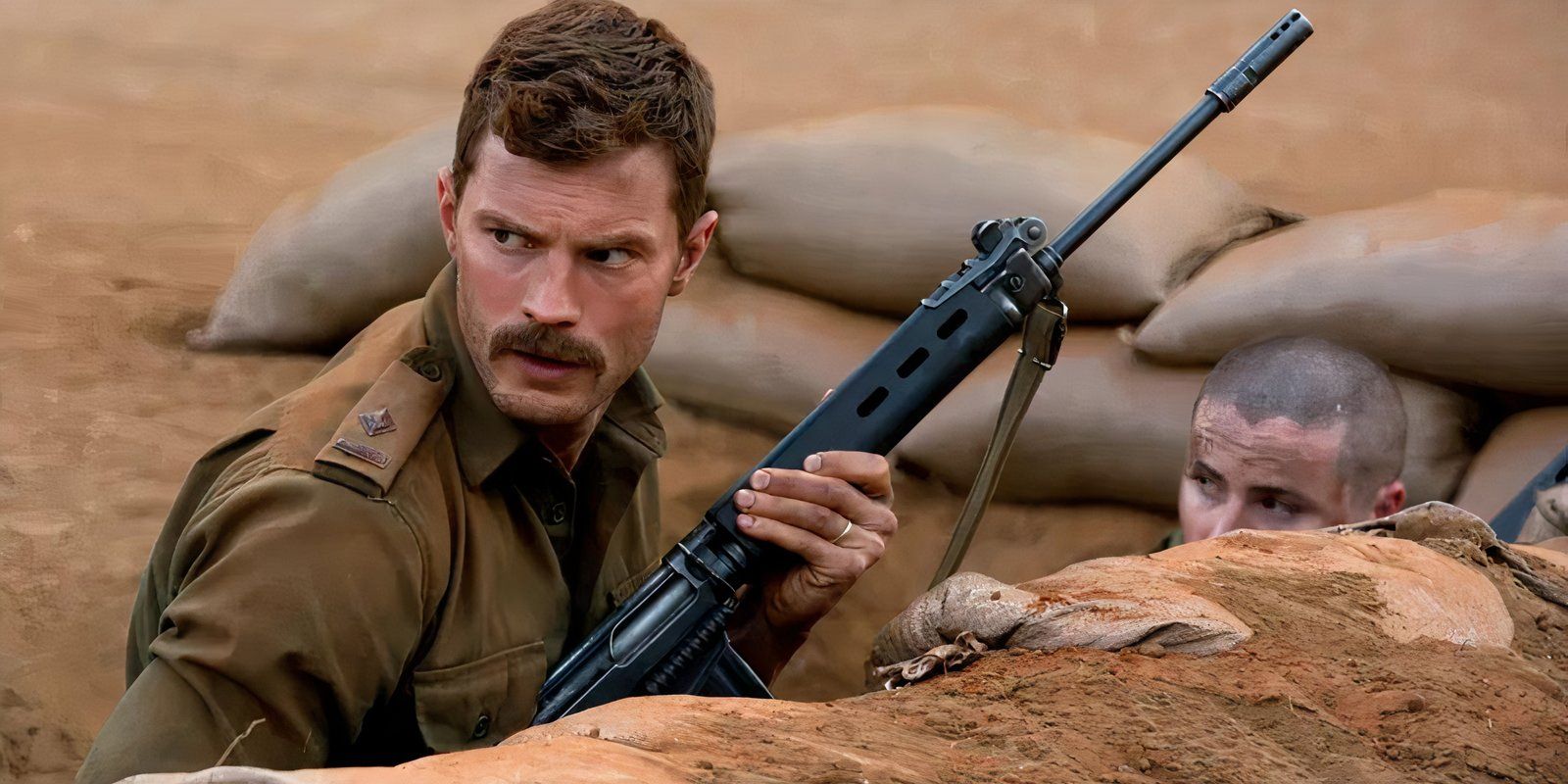 Patrick Quinlan behind a barrier holding a gun in The Siege of Jadotville