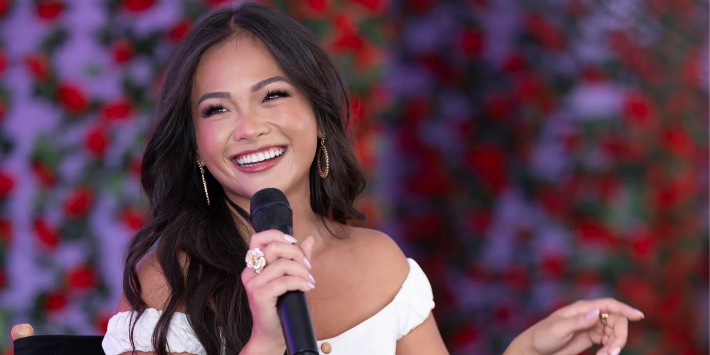 Jenn Tran smiles while holding a microphone at a promotional event for season 21 of The Bachelorette