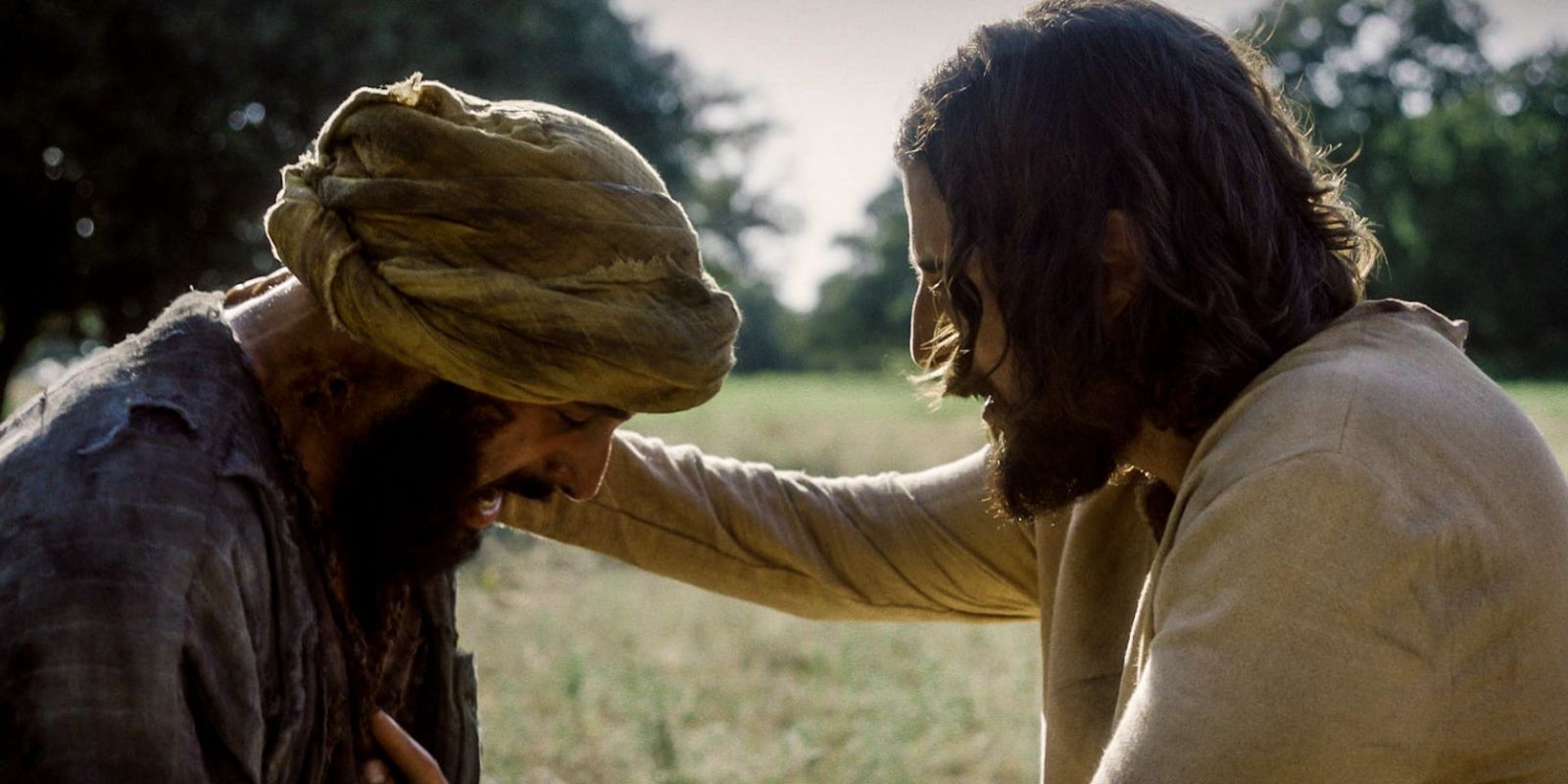 Jesus (Jonathan Roumie) sits with a leper and has His hand on the man's shoulder in 'The Chosen.'