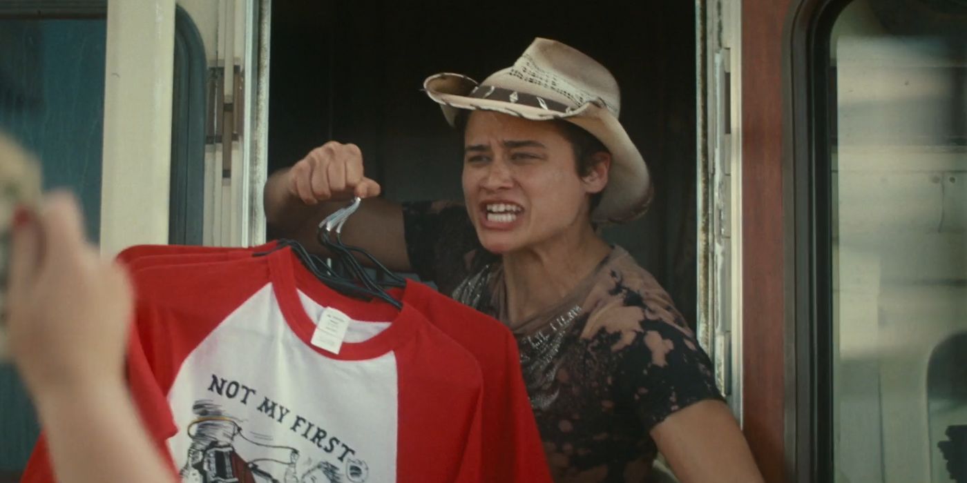 Katy O'Brian as Dani holding up a red and white t-shirt in Twisters.