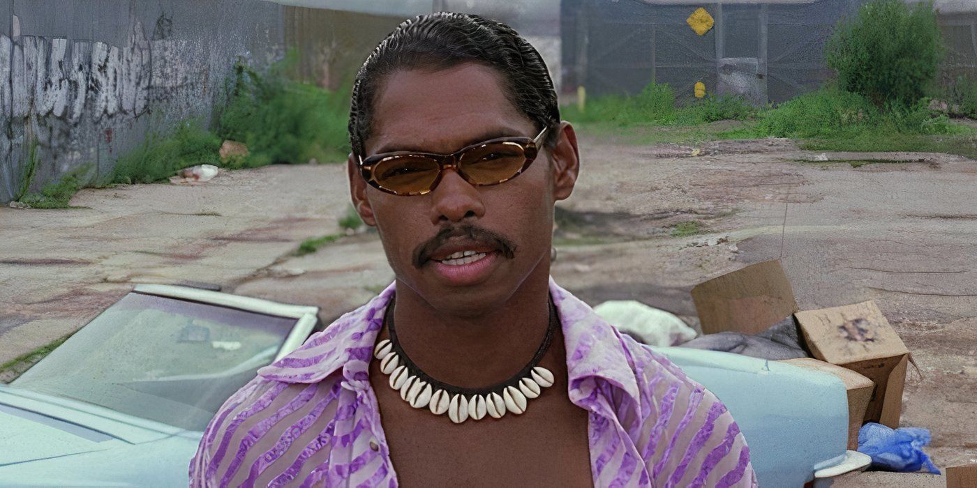 Lance Crouther wearing a shell necklace, sunglasses, and a purple shirt stands in front of a blue convertible in Pootie Tang (2001)