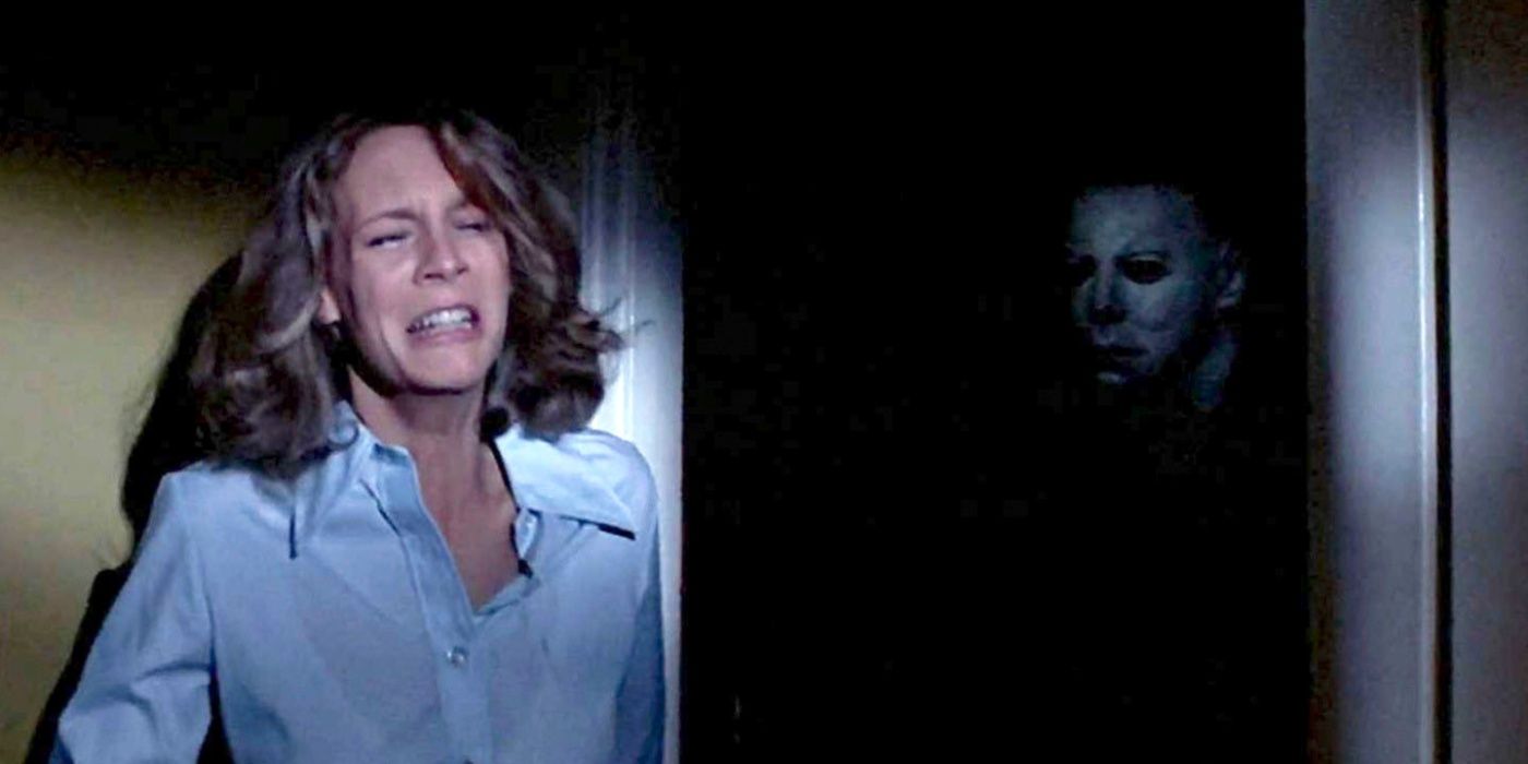 Laurie Strode hiding from Michael Myers who stands in the shadows in Halloween 2