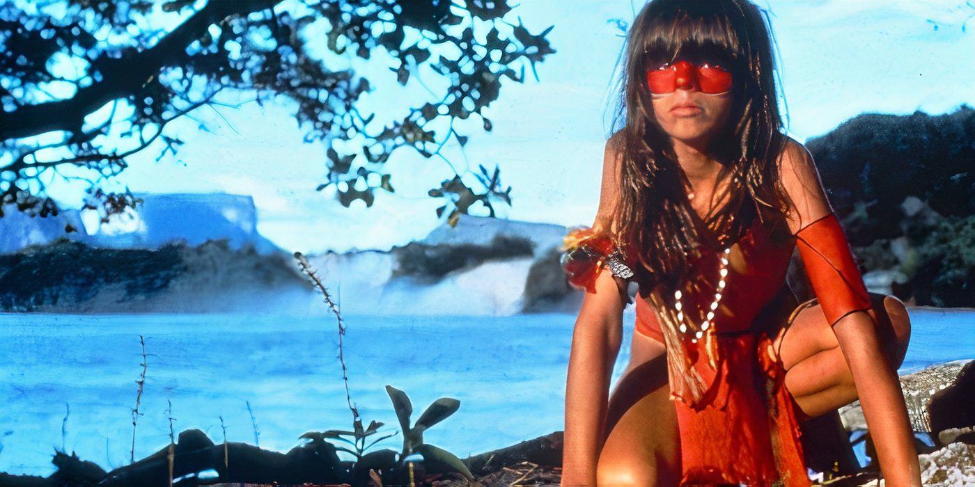 A young boy dressed in native Amazonian garb crouches along a shoreline